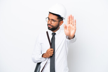 Young architect Brazilian man with helmet and holding blueprints isolated on white background making stop gesture and disappointed