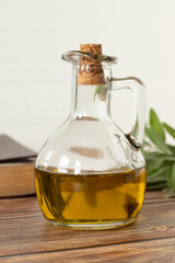 Pure olive oil in a glass jar, a closed Bible Book, and a green olive branch on a wooden table with...