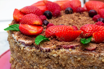 strawberry chocolate cake decorated with berries, strawberries and mint leaves
