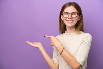 Fototapeta Young English woman isolated on purple background holding copyspace imaginary on the palm to insert an ad obraz