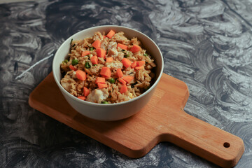 Rice with vegetables in a bowl on a wooden board