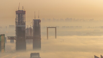 Aerial view of skyscrapers under construction covered by fog in Dubai timelapse.