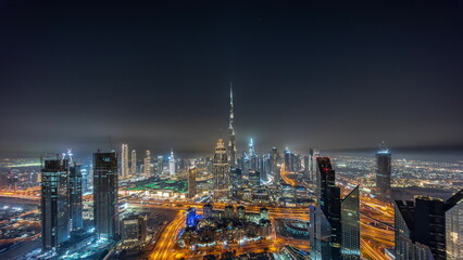 Aerial panorama of tallest towers in Dubai Downtown skyline and highway night timelapse.