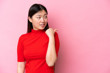 Young Chinese woman isolated on pink background pointing to the side to present a product