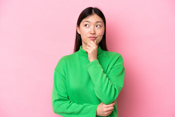 Young Chinese woman isolated on pink background thinking an idea while looking up