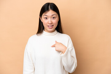 Young Chinese woman isolated on beige background with surprise facial expression