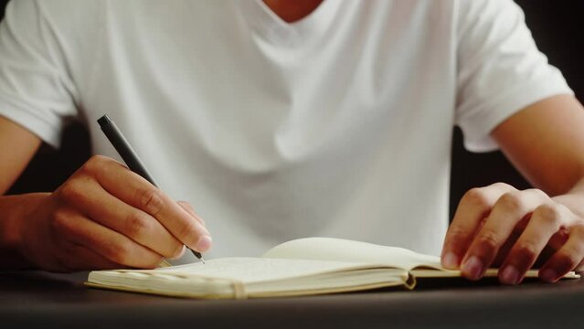 African American man writing close-up. Teenager making notes, studying, doing homework. Home education concept.