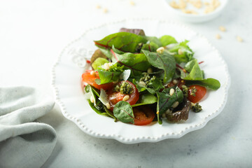 Healthy green salad with tomatoes, pesto and cheese