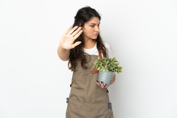 Young Russian gardener girl holding a plant isolated making stop gesture and disappointed