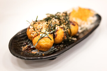 Takoyaki (deep fried squid ball), the most famous japanese snack food, served in black crockery...