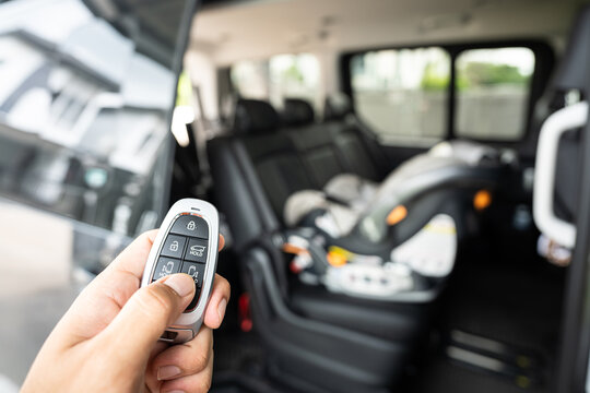Action of driver hand is active the remote key to open sliding door of a van vehicle with baby car seat is installed on the passenger seat as blurred background. Transportation technology photo