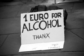 Closeup of homeless man  placard with text in english :  one euro for alcohol thanks