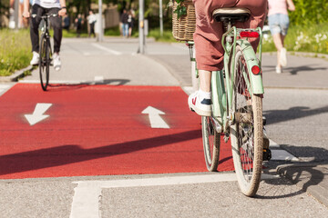 Cyclists on red bike path. Cycling on two-way bike lane. People ride bicycles in summer. Bike Traffic City Transport and people concept. 