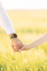 Couple in love holds each other hands on meadow.