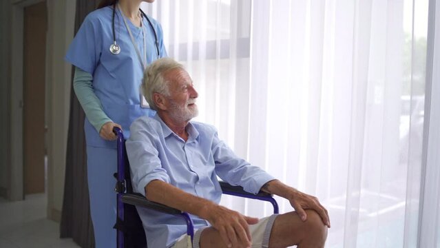 Doctors or nurses are pushing the wheelchair of an elderly patient. An old patient sits on a wheelchair while he is admitted or has a doctor's appointment at the hospital in healthcare concept