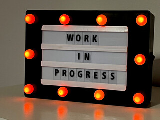 Work in Progress sign with small orange lights around it.