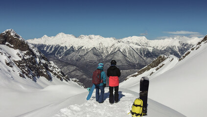 Pair of active man and woman with snowboards at snowy mountains background