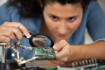 it woman using magnifying glass fixes computer hardware