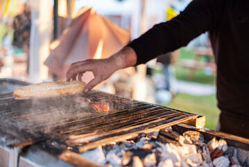 A man grilled fermented sausages with bread, close up, food carnival