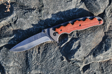 Tactical knife survival and protection difficult conditions, on stone sunny weather.