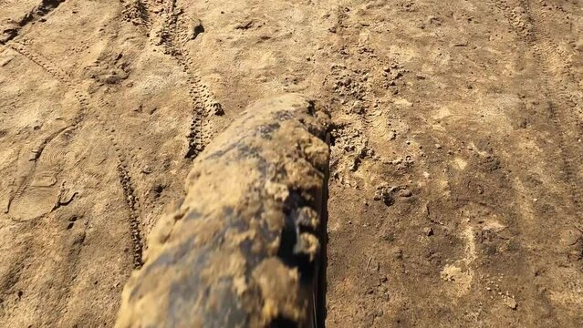 A mountain bike rides over swampy terrain with a focus on the muddy front wheel. Close up.
