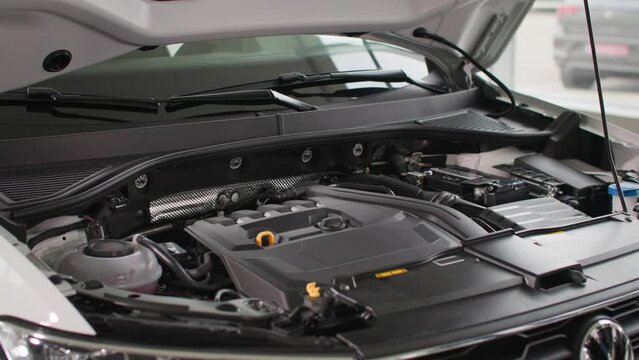 car dealership, exhibition model of a vehicle engine under hood of a new car model in a automobile center, close-up