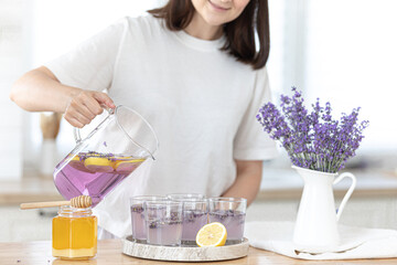 A young girl makes lemonade from lemons and lavender. Woman making a summer drink.
