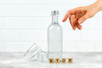 Glass Bottle of vodka, tequila and empty shot glass on grey background, copy space. Stop alcoholism...