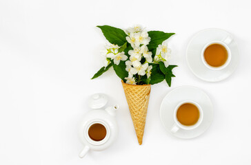 jasmine tea in white cups and teapot, medicinal herbal drink for diet food, healthy lifestyle, sprigs of blooming jasmine in a cone on a white background, top view