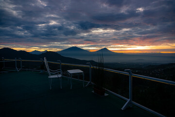 Terrace with view of nature and mountains at sunrise. There are mount Andong, Telomoyo, Merbabu and Merapi Volcano. The sky is cloudy. This place named Wanamukti Siguede, Magelang, Indonesia