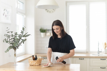Young woman cleans the kitchen with eco products.