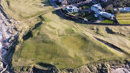 Aerial view looking out over North Berwick town and golf course with waves crashing onto the shore. North Berwick Scotland. 