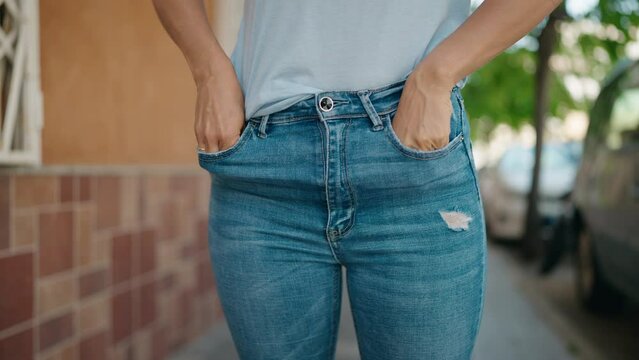 Young woman showing empty pockets at street