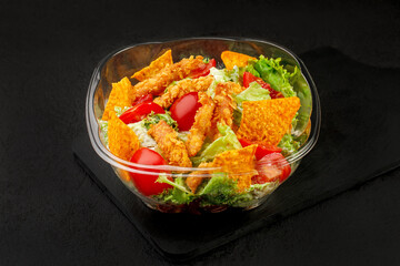 Nachos salad with crispy thrips and nugets on a black background