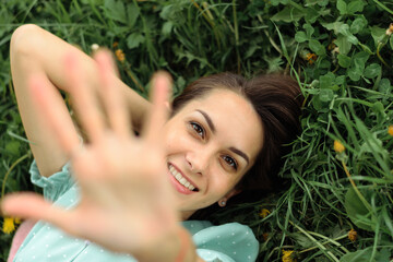 Naklejka premium Portrait of a beautiful happy young woman lying on the grass on a summer day, top view.Closeness to nature,summer concept.