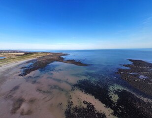 Aerial view of the incredible coastline of Scotland with views of the North Sea. Blue sky background with ocean waves. 