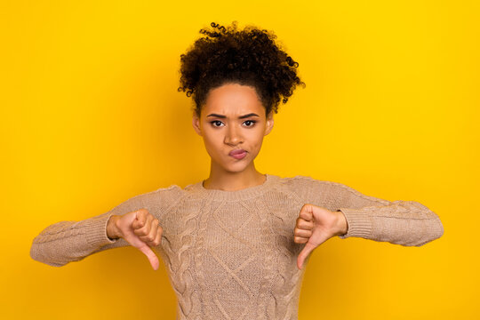 Photo of unhappy upset woman wear beige sweater showing two thumbs down isolated yellow color background