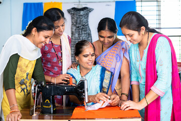 group of woman at tailoring class discuissing with teacher about cloth and stitching during...