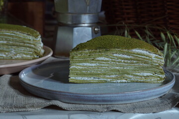 Puff slices of green pancake pie with matcha tea on plates.