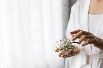 The bride holds a boutonniere in her hands. Horizontal photo