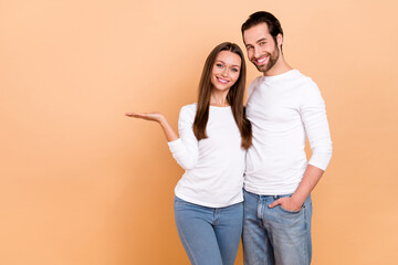 Photo of lovely millennial brunette couple hold empty space wear white cloth isolated on beige color background