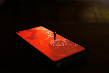 Business man figure standing on a smartphone with a picture of bitcoins.