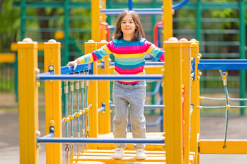 little cute girl on a childrens ladder on a bright yellow playground