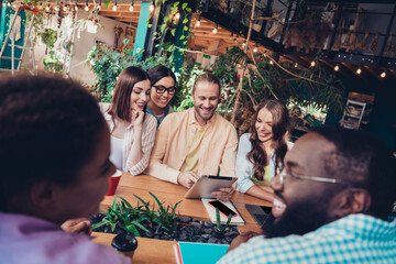 Portrait of friendly satisfied students company sitting cafe use tablet chatting conversation indoors