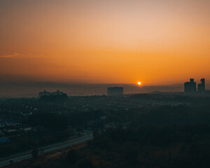 Amazing aerial view on the orange sky, sunset sun and clouds near the city.