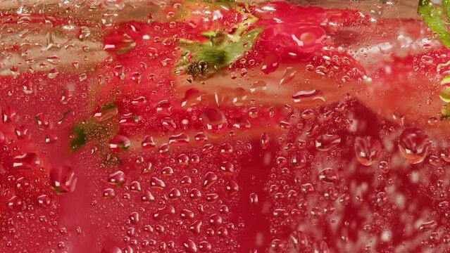Cooking strawberry sweet cocktail, cold lemonade with red berries, carbonated water with floating fruits.