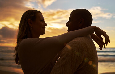 Loving young affectionate interracial couple in silhouette facing each other while spending time...