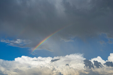 A rainbow arc across the sky during a rainstorm