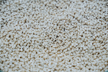 Granules of white plastic shot close-up, a pile of small crumbs of plastic, components of...
