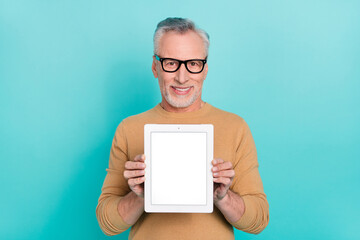 Photo of cheerful person hold demonstrate empty space tablet screen isolated on turquoise color...